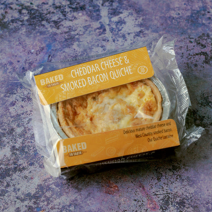A mini quiche in plastic wrapper and foil tray.