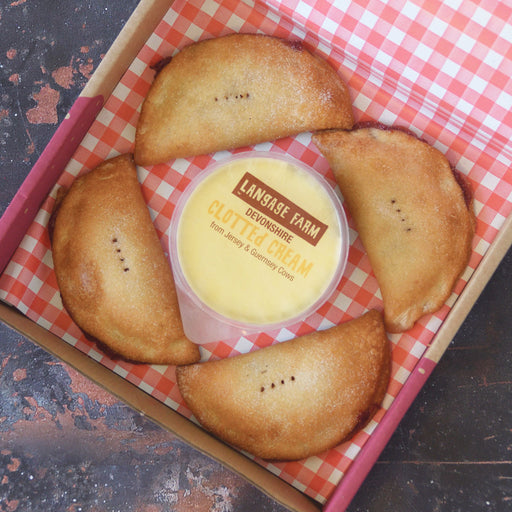 A bix of 4 gluten free strawberry pasties with a pot of cream in the middle.