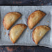 Four gluten free strawberry pasties, freshly baked on a tray.